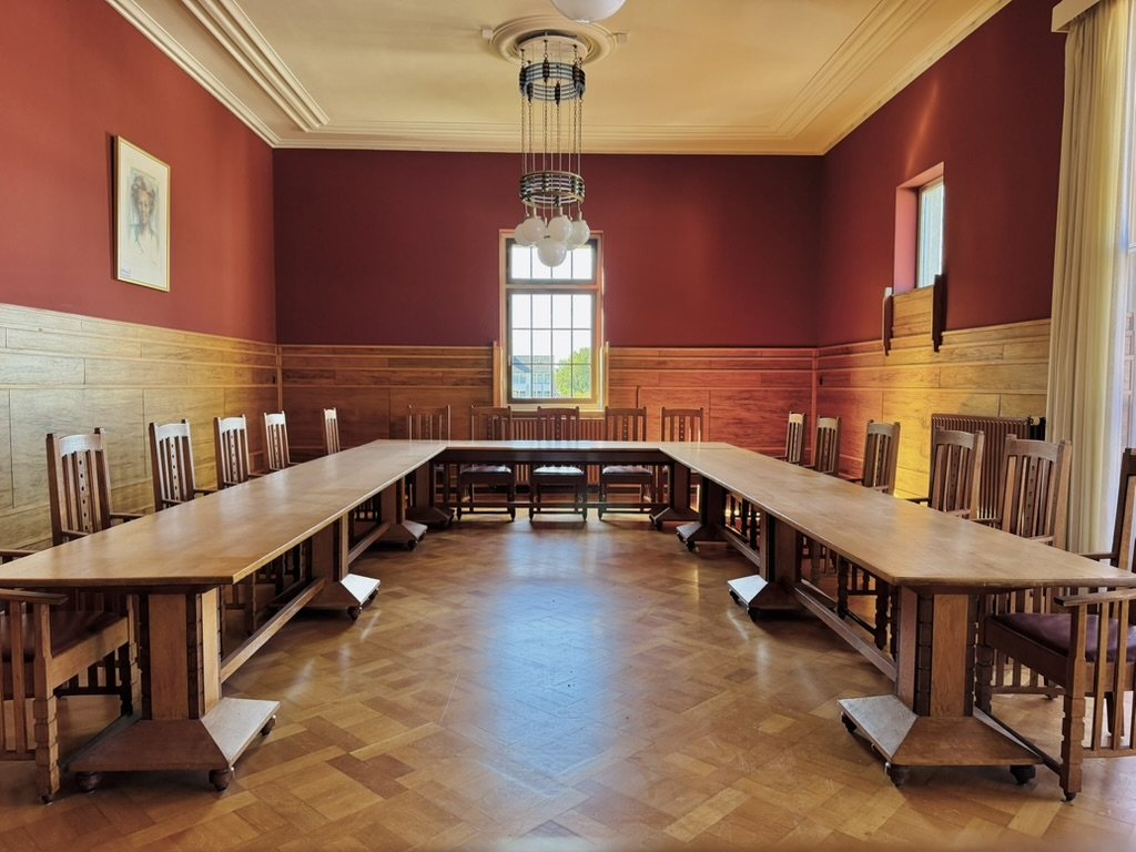 De Raadzaal met houten vergadertafels